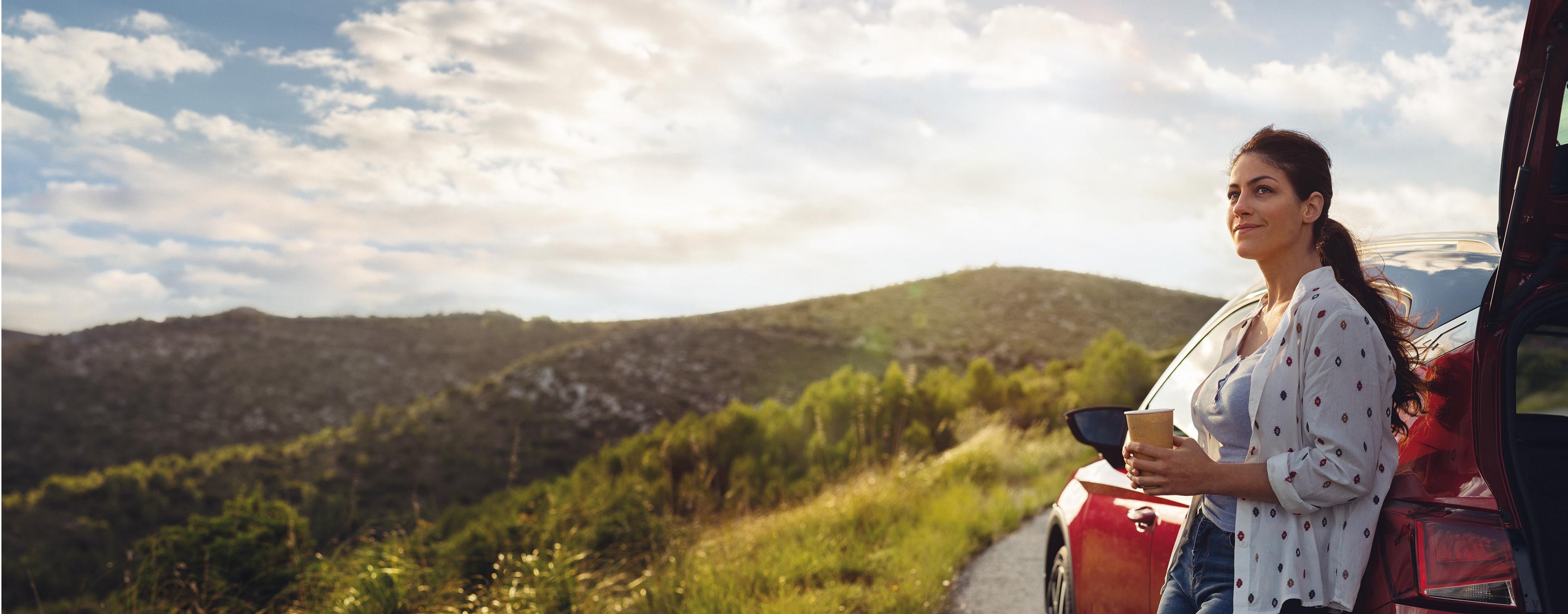 SEAT services de voitures neuves et d'entretien - SEAT Arona crossover SUV garé en surplomb d'une vallée avec une femme s'appuyant sur la voiture.