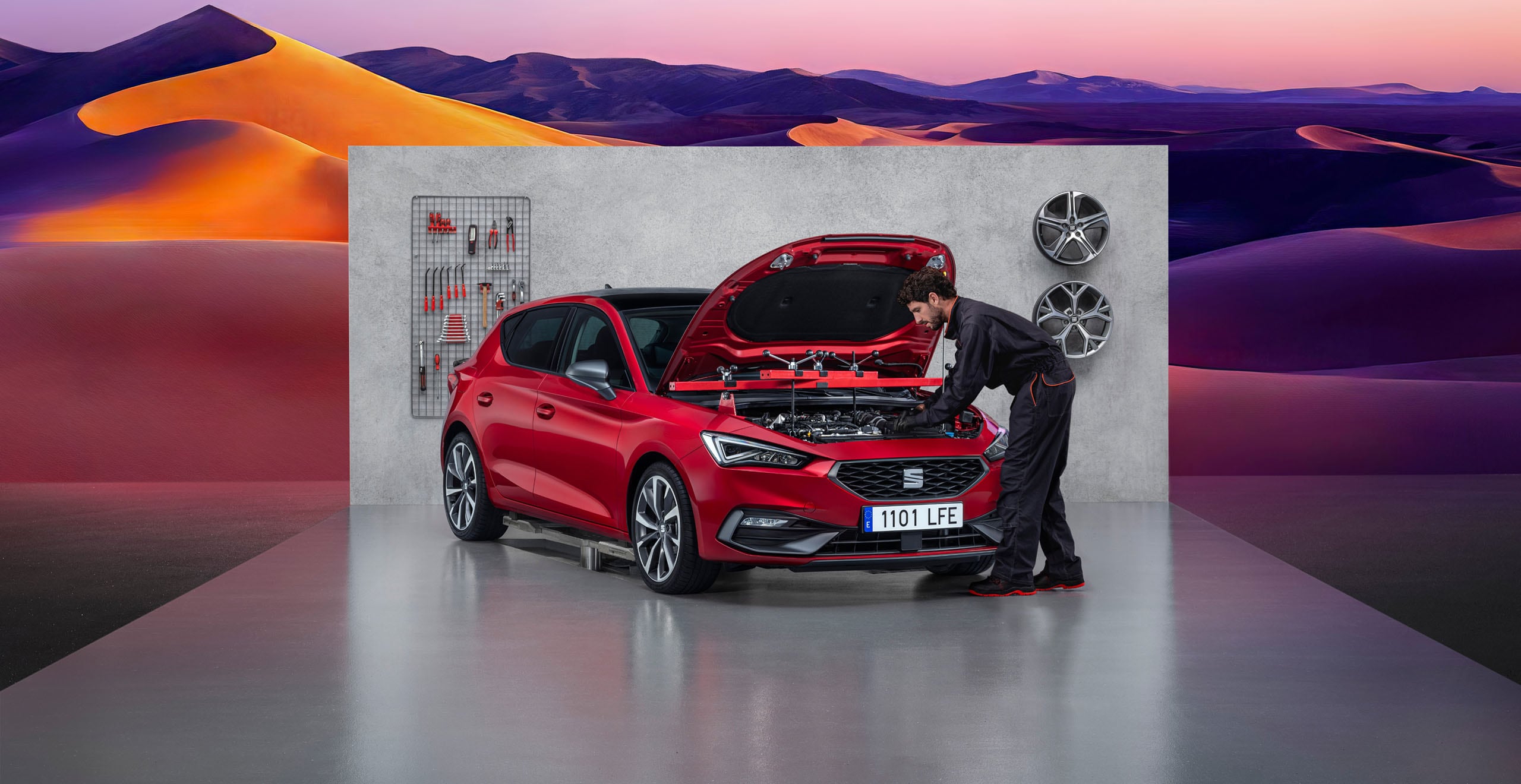 Technicien automobile effectuant une intervention sur le moteur d’une SEAT Leon rouge, capot ouvert, dans un atelier d’entretien.