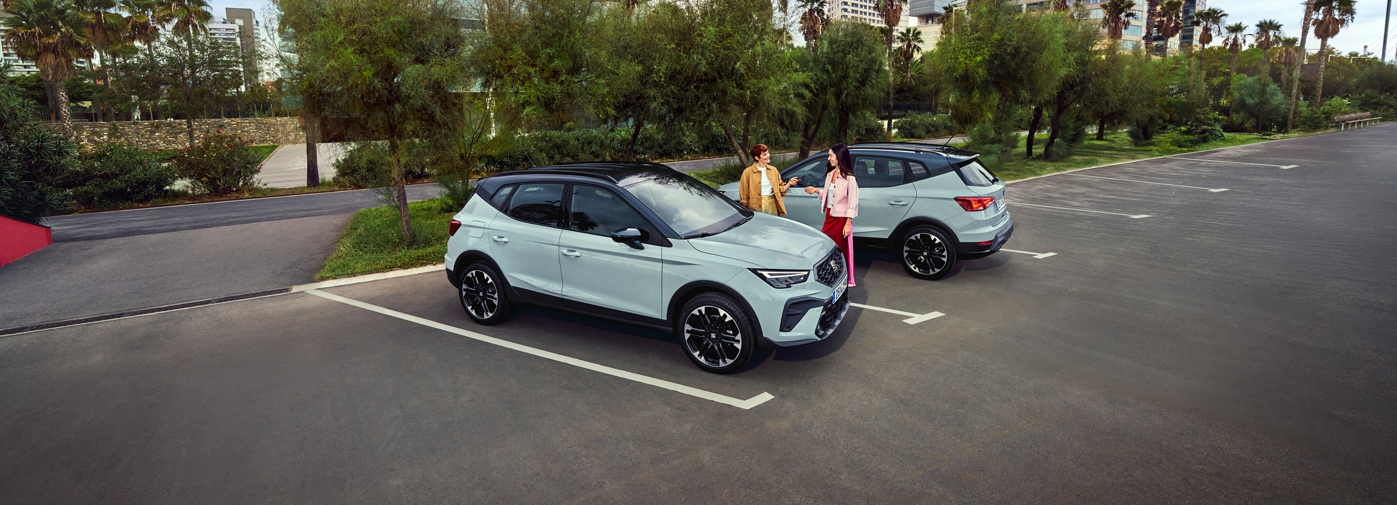 Deux voitures SEAT Arona garées à l'extérieur dans un cadre urbain ensoleillé.