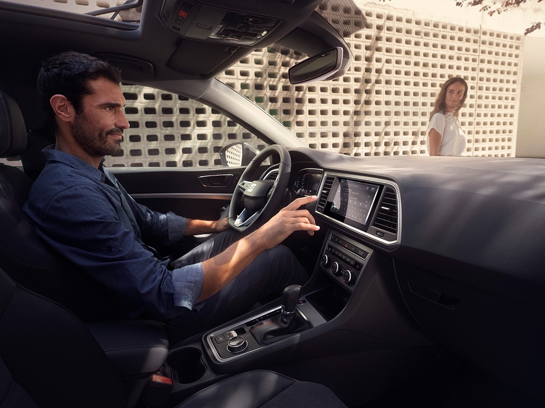 Un homme profite de la conduite de la seat ateca pendant qu’une femme regarde à l’extérieur.