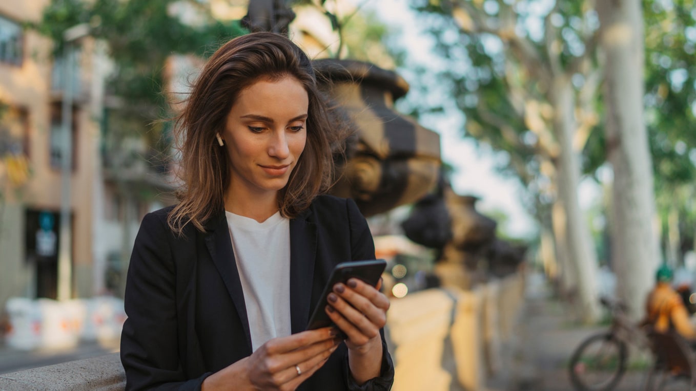 femme en milieu urbain tenant son smartphone, utilisant la fonction seat connect.