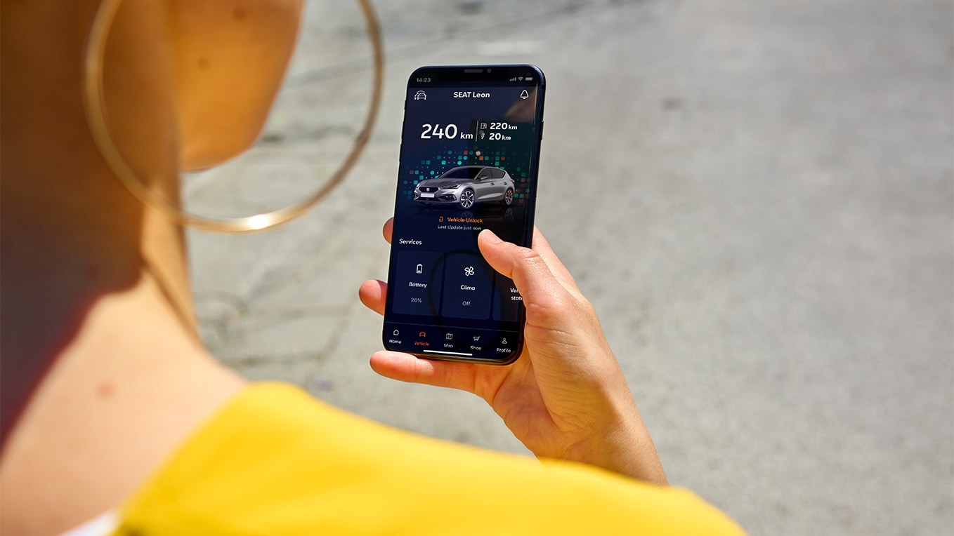 une personne tenant un smartphone et utilisant l’application my seat, une fonctionnalité de seat connect qui offre un accès à distance au véhicule et ses fonctionnalités.