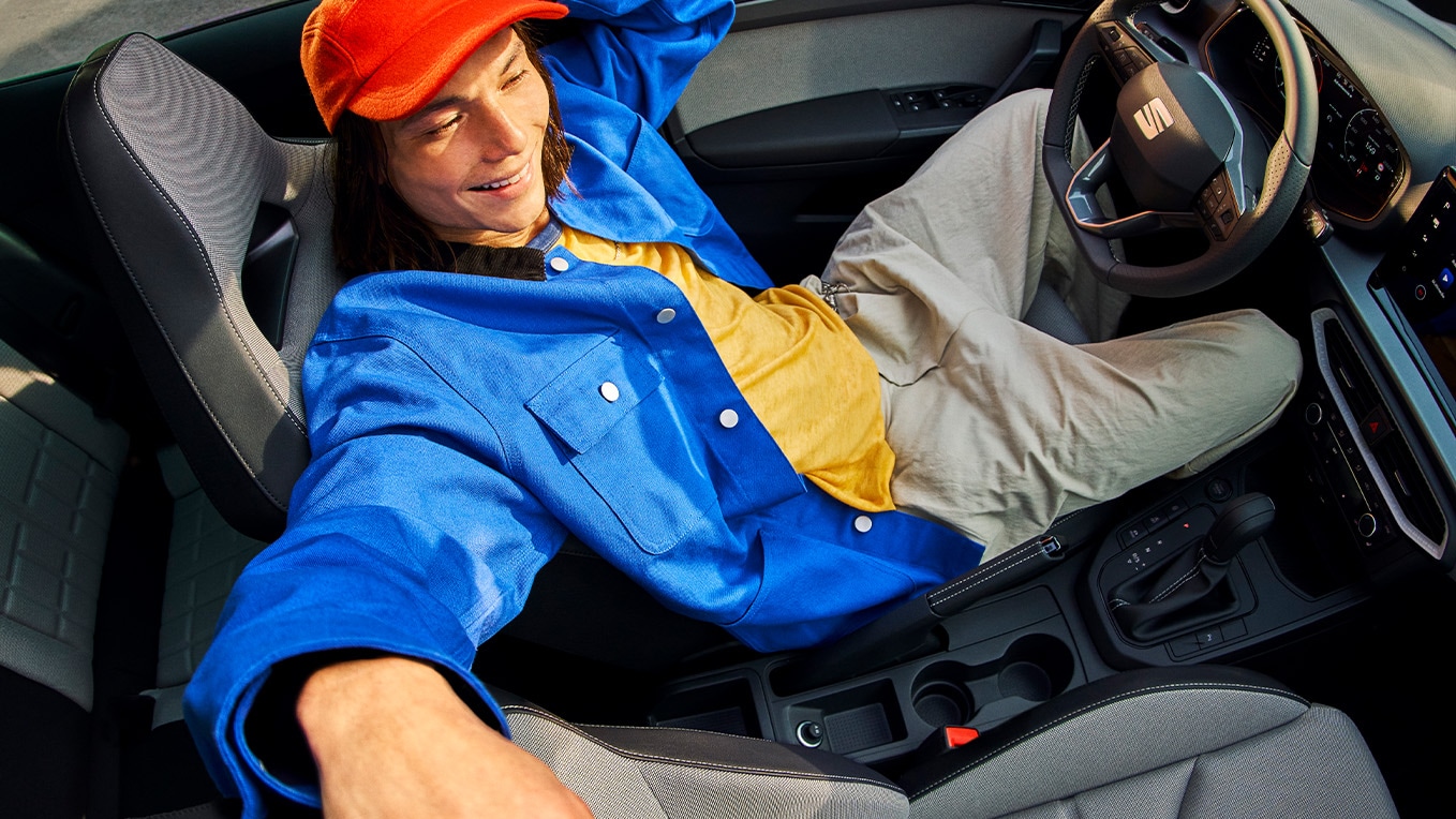  Intérieur de la SEAT Ibiza  montrant un tableau de bord moderne, des sièges élégants et un toit ouvrant, avec une personne allongée à l'intérieur de la voiture. 