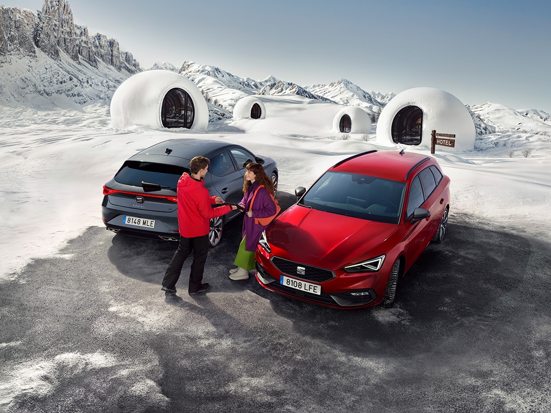 Deux SEAT Leon (5D et SP) garées dans un village de montagne avec deux personnes se tenant entre elles.