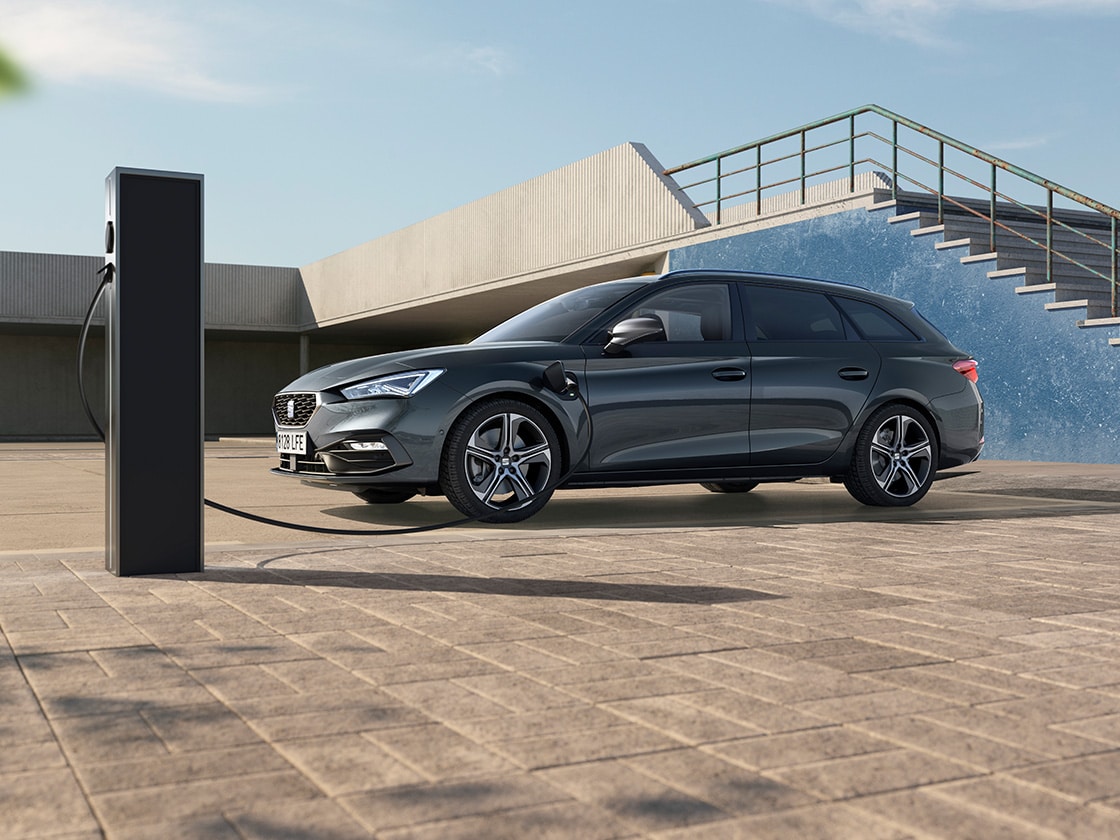 Vue arrière latérale d'une SEAT Leon NF Sportstourer dans un environnement ensoleillé et des escaliers en arrière-plan.