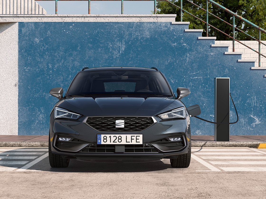 La seat leon sportstourer e-HYBRID, une voiture hybride électrique, garée sur une place de parking à côté d’une station de recharge extérieure, mettant en avant la fonctionnalité de l’e-gestionnaire pour une valeur ajoutée impressionnante.