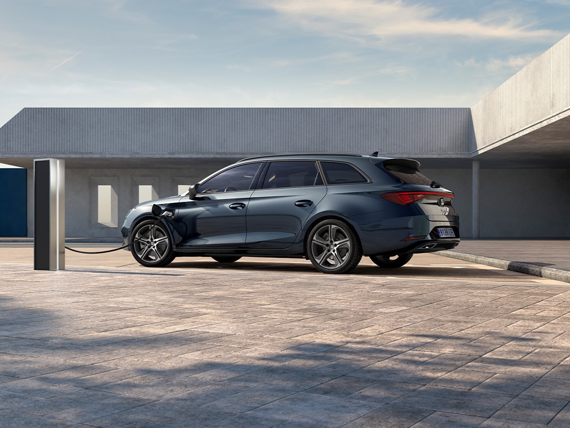 Seat leon sportstourer à hayon 2025, véhicule hybride rechargeable et chargeur seat. Garée et en train de recharger en extérieur, avec des jantes en alliage à rayons, un éclairage d’ambiance intérieur et des sièges avant chauffants.