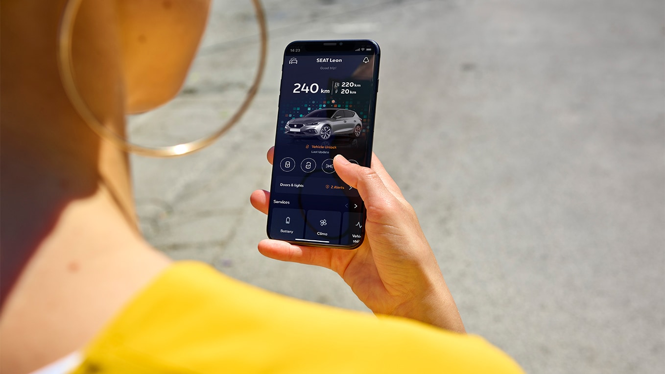 Une personne tenant un smartphone utilisant l’application my seat, une fonctionnalité de seat connect, pour l’accès à distance et les fonctionnalités du véhicule.
