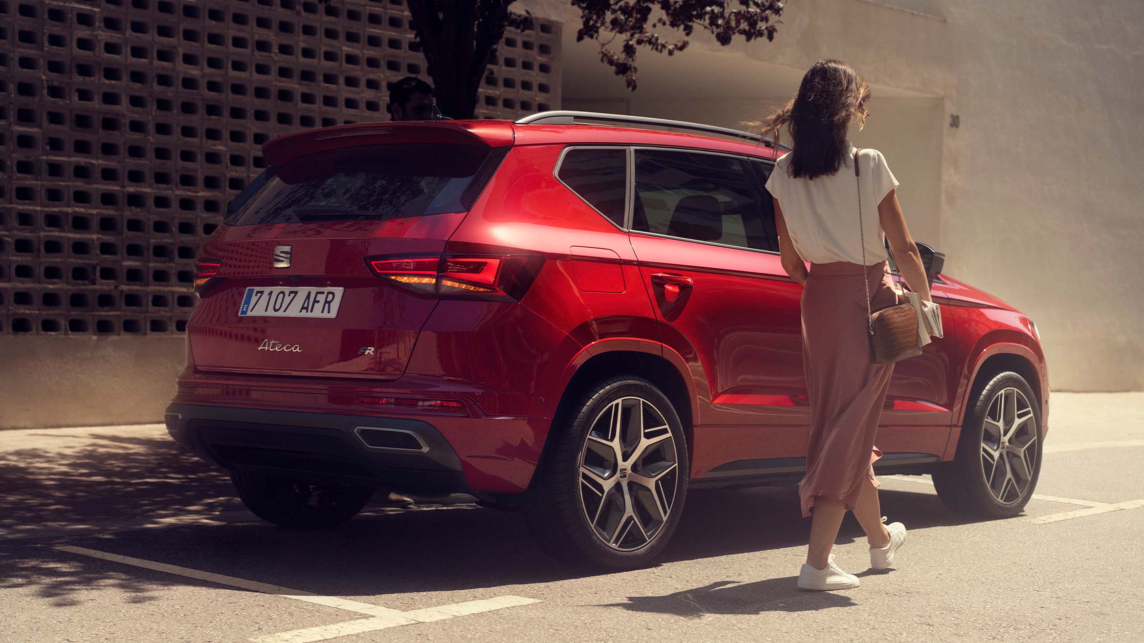 Femme marchant à côté d'une SEAT Ateca 2024 Rouge