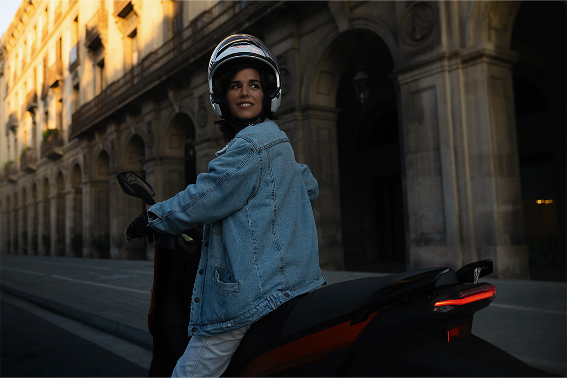 Femme au guidon de son scooter électrique SEAT MÓ 125, dont la vitesse maximale est de 95 km/h