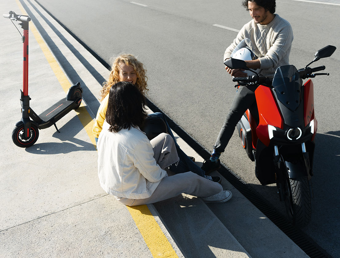 group of friends sitting with their SEAT MÓ 125 and SEAT MÓ 65 electric scooters in the city