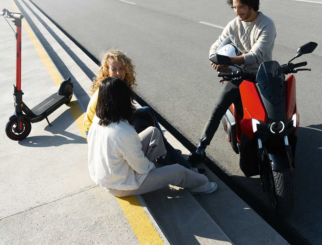 group of friends sitting with their SEAT MÓ 125 and SEAT MÓ 65 electric scooters in the city