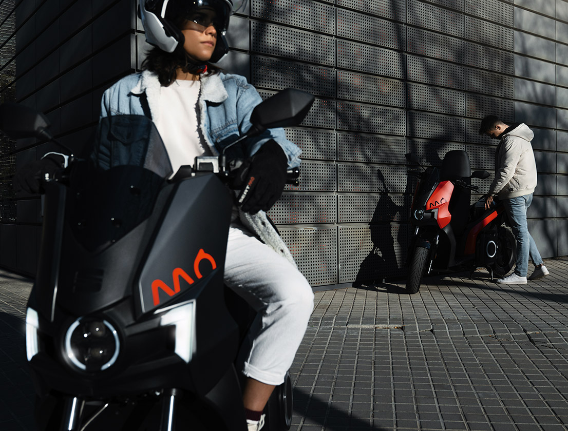 two friends riding SEAT MÓ 65 and SEAT MÓ 125 electric scooters in the city