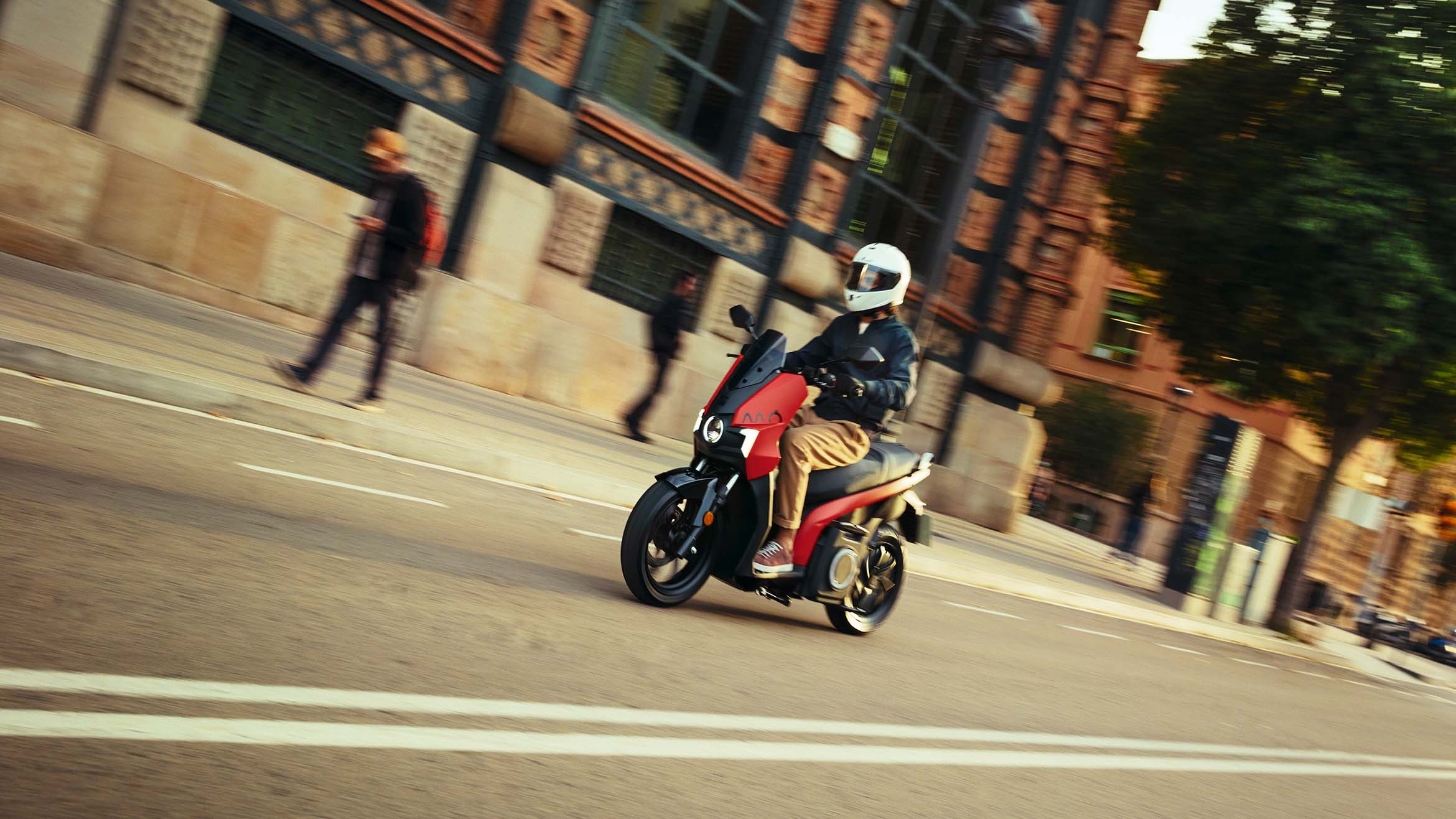 person wearing a helmet riding their SEAT MÓ 125 electric scooter in the city