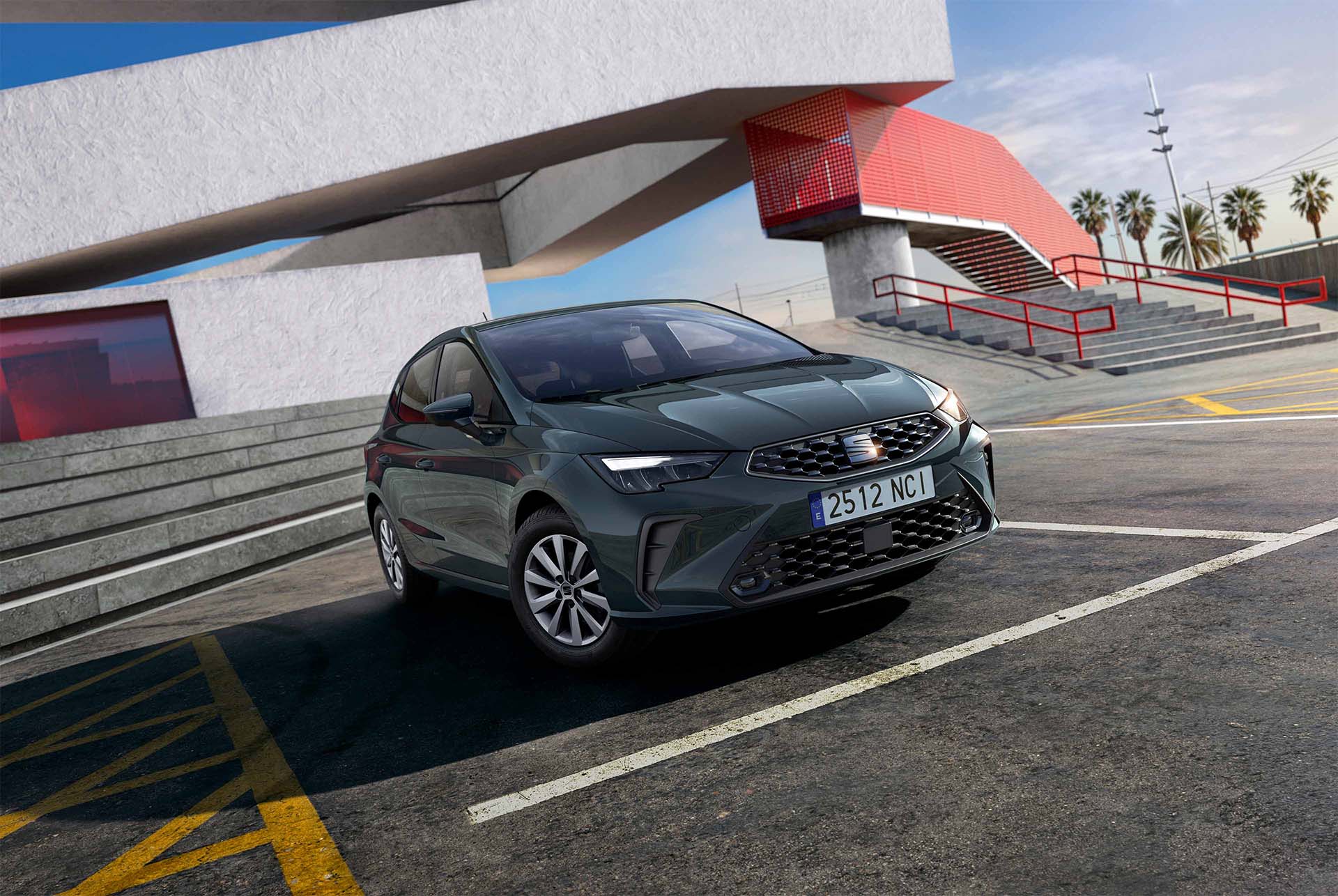 Vue d’une citadine SEAT Ibiza Style dans une teinte vert pâle, présentée dans un environnement urbain aux lignes architecturales marquées, avec des structures angulaires en béton et des palmiers visibles en arrière-plan.